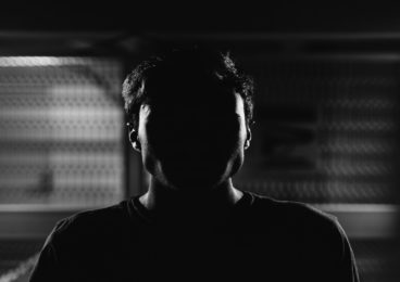 cryptocurrency and criminal activity. A black-and-white photo of a man with his face obscured.
